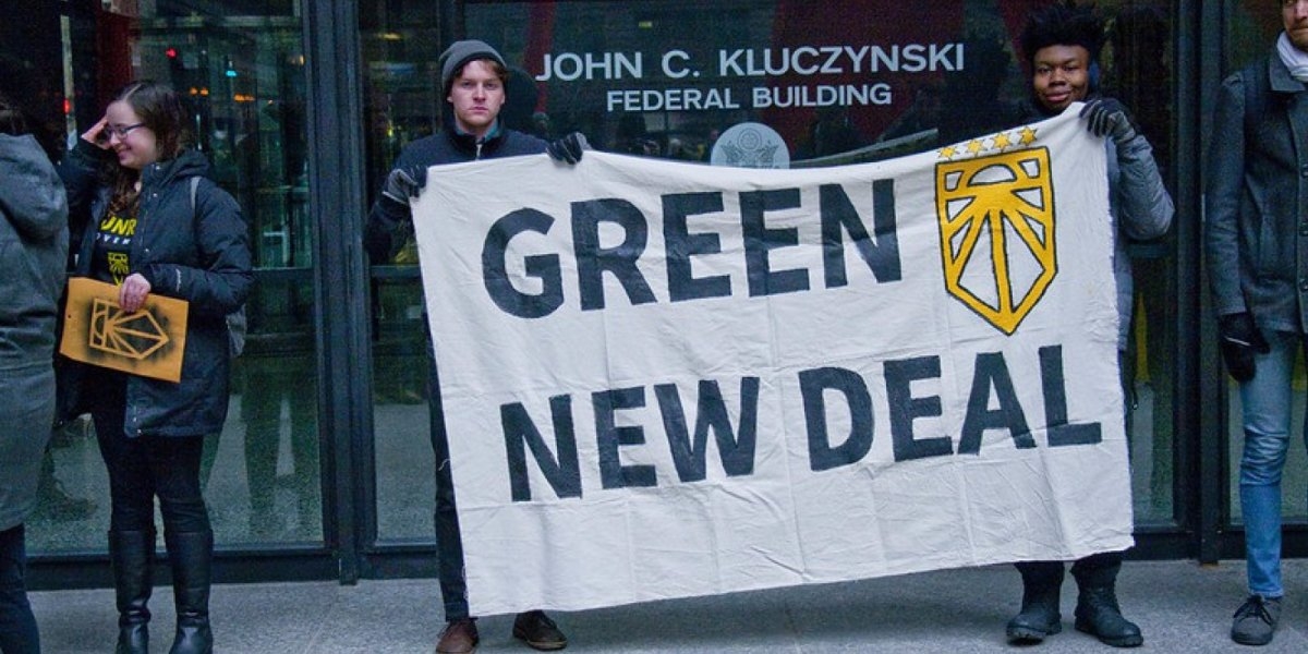 Two young men holding up a sign saying "Green new deal"