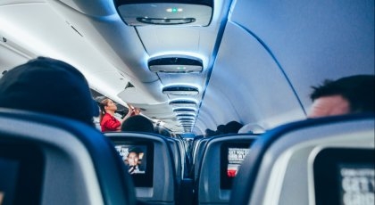 Innsiden av en flykabin med passasherer og stewardess