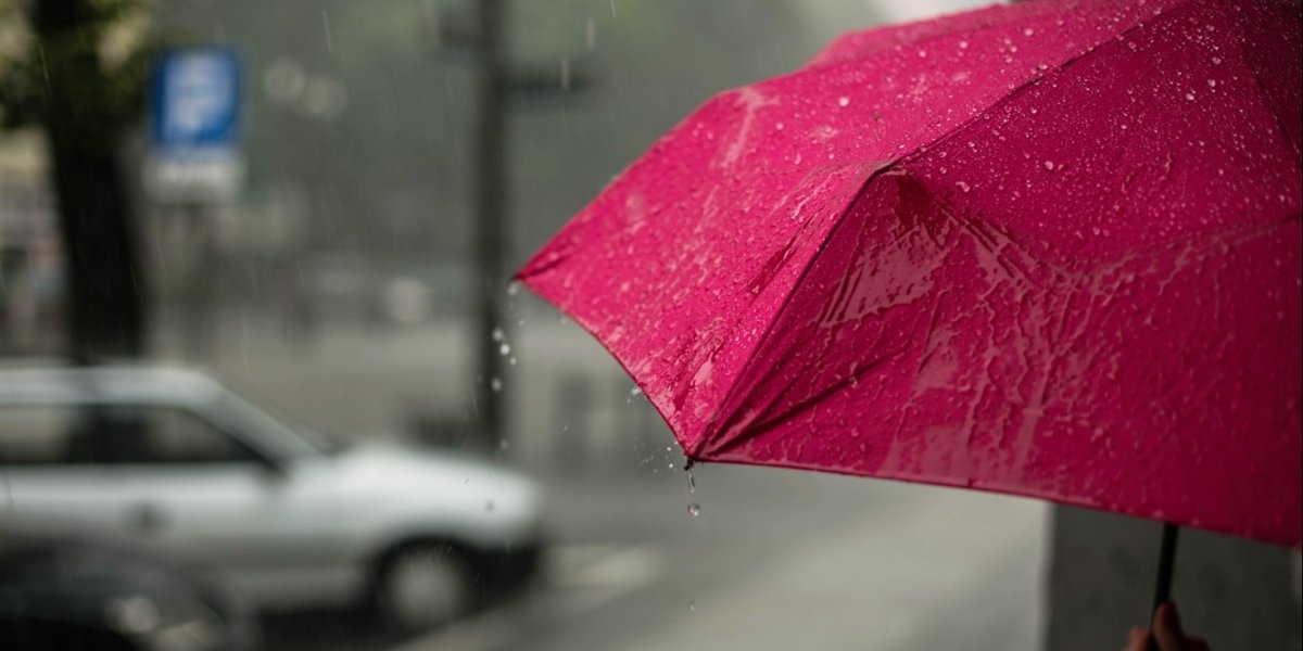 Regnvann drypper fra en rosa paraply
