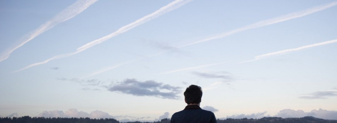 En mann ser på flystriper på himmelen