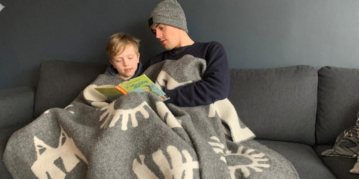 Barn i sofa med pledd og bok