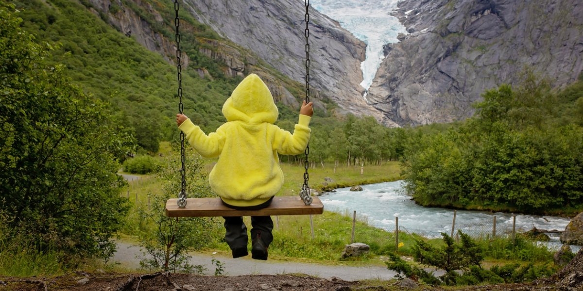Child, cute blond boy, toddler enjoying the amazing view of the glacier in Jostedalsbreen national park