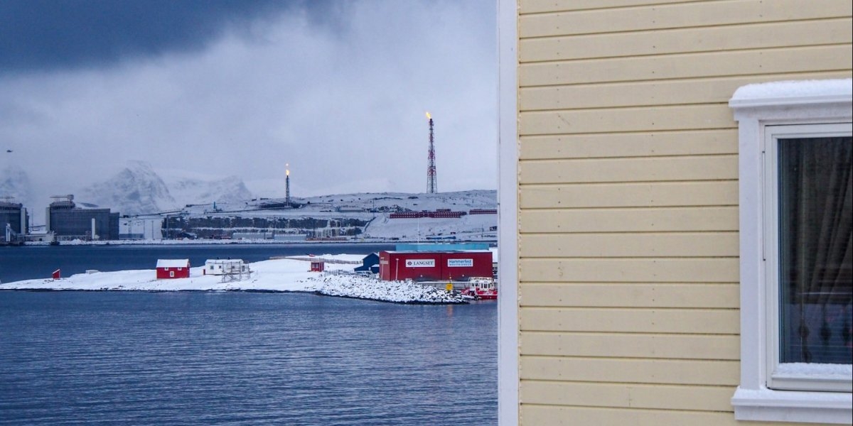 Husvegg foran kaldt industrilandskap i Finnmark.
