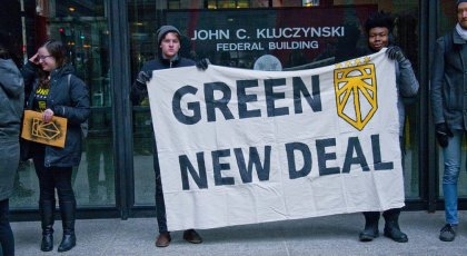 Foto av to unge menn som holder opp en plakat der det står "Green new deal".